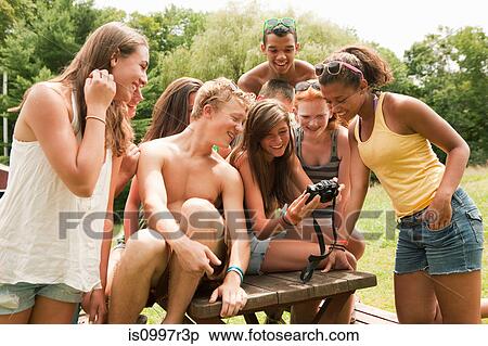 Stock Photography - Teenagers looking at pictures on a friend's camera together. Fotosearch