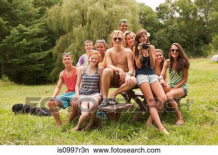 Teenagers relaxing together, sitting on a picnic table in the countryside View Large Photo Image Picture - Teenagers relaxing together, sitting on a picnic table in the countryside. Fotosearch