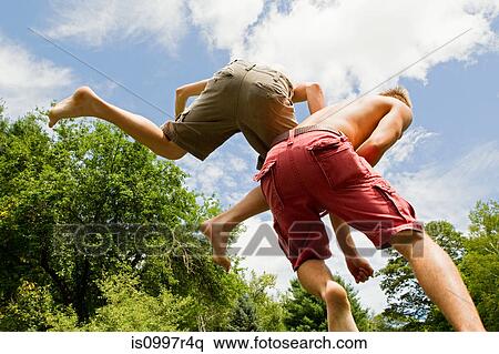 Two teenage boys bouncing high in the air View Large Photo Image Stock Photography - Two teenage boys bouncing high in the air. Fotosearch