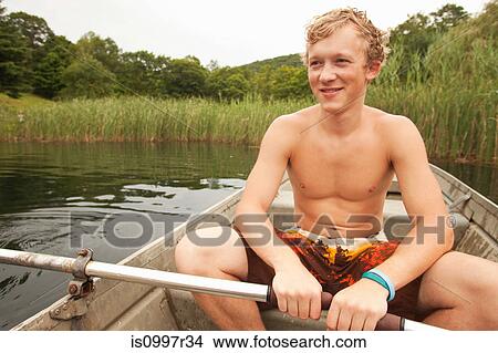 Picture - Young man in a row boat on a lake during summer vacation. Fotosearch