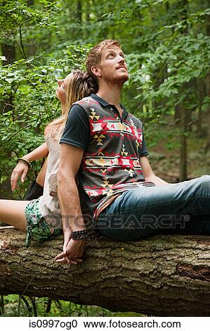 Couple leaning against each other on log in forest View Large Photo Image Stock Image - Couple leaning against each other on log in forest. Fotosearch