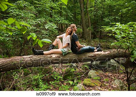 Couple leaning against each other on log in forest View Large Photo Image Stock Photo - Couple leaning against each other on log in forest. Fotosearch