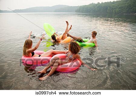 Picture - Friends playing in inflatable rings on lake. Fotosearch