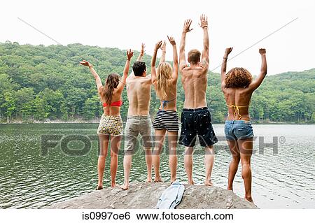 Friends standing together and cheering on rock at lakeside View Large Photo Image Stock Photograph - Friends standing together and cheering on rock at lakeside. Fotosearch