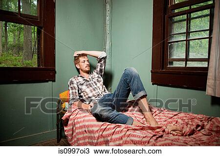 Mid adult man sitting on bed in cabin View Large Photo Image Stock Image - Mid adult man sitting on bed in cabin. Fotosearch