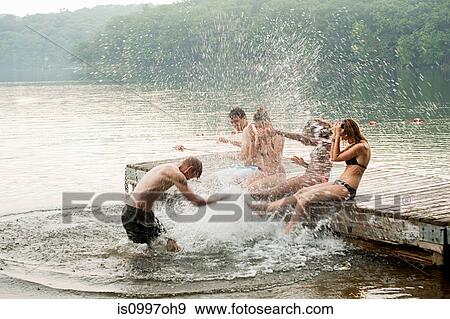 Mid adult man splashing friends in lake View Large Photo Image Stock Photo - Mid adult man splashing friends in lake. Fotosearch