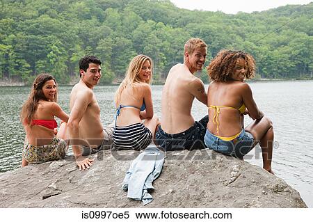 Portrait of friends sitting on rock at lakeside View Large Photo Image Stock Photography - Portrait of friends sitting on rock at lakeside. Fotosearch