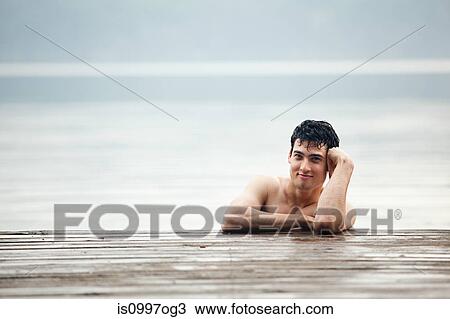 Portrait of young man leaning on pier in lake View Large Photo Image Stock Image - Portrait of young man leaning on pier in lake. Fotosearch