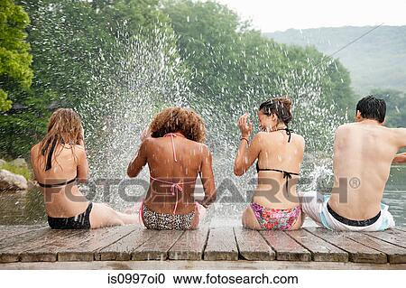Rear view of young friends splashing water in lake View Large Photo Image Stock Image - Rear view of young friends splashing water in lake. Fotosearch
