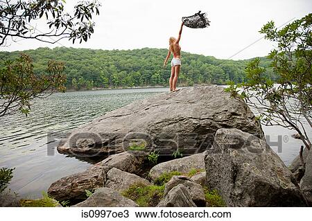 Young woman holding blanket on rock at lake View Large Photo Image Stock Image - Young woman holding blanket on rock at lake. Fotosearch