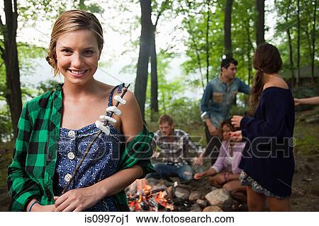 Young woman holding food cooked on campfire in forest View Large Photo Image Stock Image - Young woman holding food cooked on campfire in forest. Fotosearch