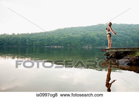 Young woman standing on pier over lake View Large Photo Image Stock Photo - Young woman standing on pier over lake. Fotosearch