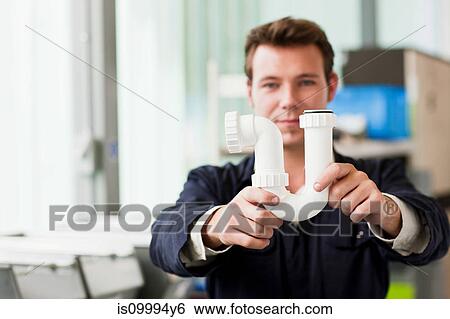 Apprentice plumber holding up waste pipe View Large Photo Image Stock Photograph - Apprentice plumber holding up waste pipe. Fotosearch