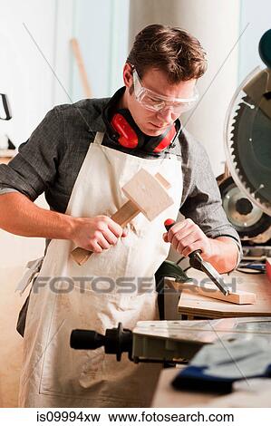 Carpenter carving wood with mallet and chisel View Large Photo Image Stock Photo - Carpenter carving wood with mallet and chisel. Fotosearch