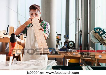Picture - Carpenter checking angle of wood in workshop. Fotosearch