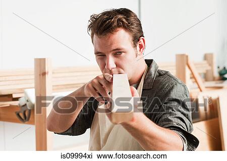 Stock Image - Carpenter checking angle of wood in workshop. Fotosearch