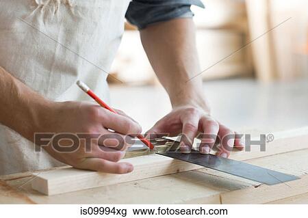 Stock Image - Carpenter using mitre in workshop. Fotosearch
