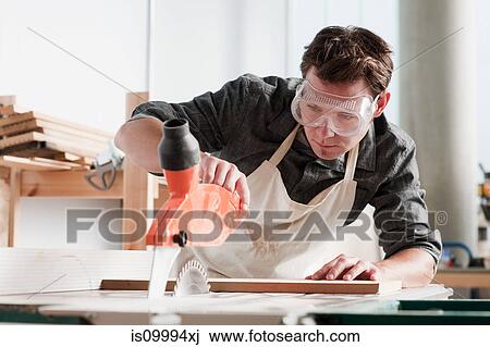 Carpenter using saw in workshop View Large Photo Image Stock Image - Carpenter using saw in workshop. Fotosearch