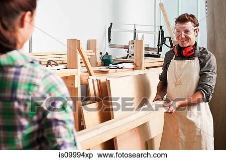 Stock Photography - Carpenters carrying wood in workshop. Fotosearch