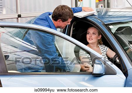 Mechanic speaking to woman in car View Large Photo Image Stock Photograph - Mechanic speaking to woman in car. Fotosearch