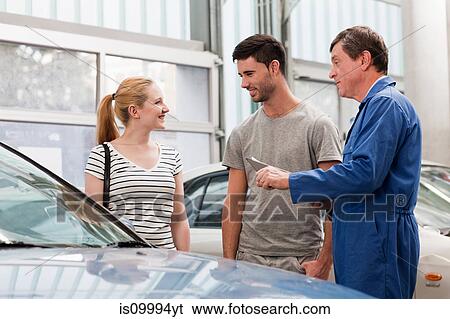 Stock Photograph - Mechanics talking to woman about car. Fotosearch