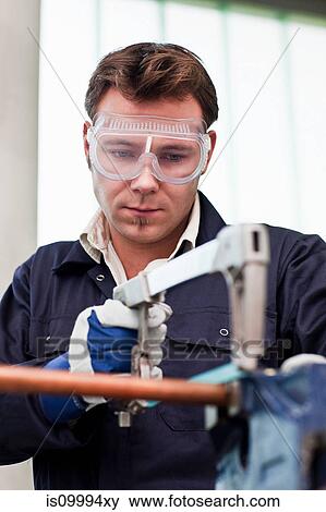Plumber cutting into copper pipe in workshop View Large Photo Image Stock Photo - Plumber cutting into copper pipe in workshop. Fotosearch