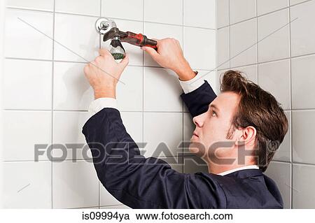 Stock Image - Plumber fixing shower head. Fotosearch