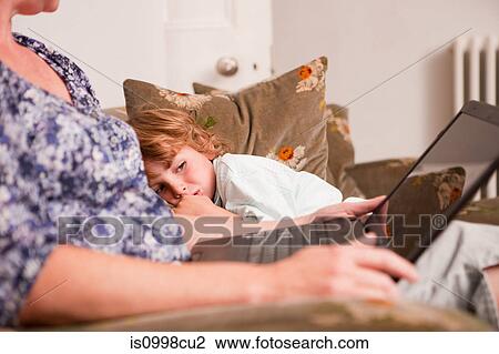 Stock Image - Boy watching mother use laptop. Fotosearch