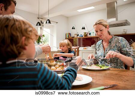 Family sitting down and eating a healthy meal together View Large Photo Image Stock Photo - Family sitting down and eating a healthy meal together. Fotosearch