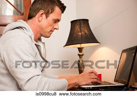 Man using a laptop at home View Large Photo Image Stock Photo - Man using a laptop at home. Fotosearch