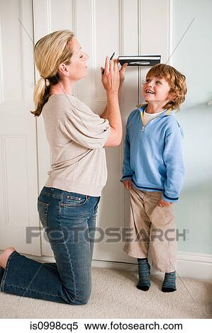 Mother measuring her son against a door with a book View Large Photo Image Stock Photography - Mother measuring her son against a door with a book. Fotosearch