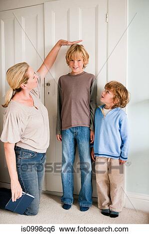 Mother measuring her sons at home View Large Photo Image Stock Photograph - Mother measuring her sons at home. Fotosearch