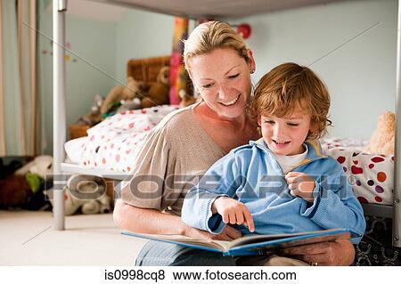 Stock Photo - Mother reading a book with her son in his bedroom. Fotosearch