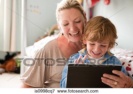 Stock Photo - Mother using a digital tablet with her son. Fotosearch