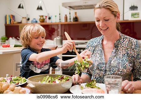 Son helping to serve salad for mother at the family dinner table View Large Photo Image Stock Photograph - Son helping to serve salad for mother at the family dinner table. Fotosearch