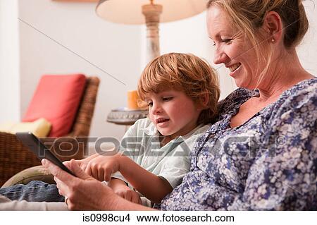 Son using a digital tablet with his mother View Large Photo Image Picture - Son using a digital tablet with his mother. Fotosearch