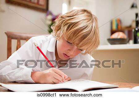 Young boy at home writing in school text book at the dining table View Large Photo Image Stock Image - Young boy at home writing in school text book at the dining table. Fotosearch
