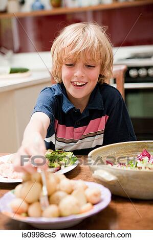 Young boy at the family dinner table helping himself to potatoes View Large Photo Image Stock Photography - Young boy at the family dinner table helping himself to potatoes. Fotosearch