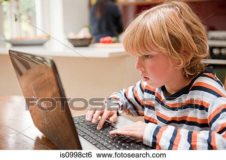 Young boy looking at a laptop monitor while typing View Large Photo Image Stock Photograph - Young boy looking at a laptop monitor while typing. Fotosearch