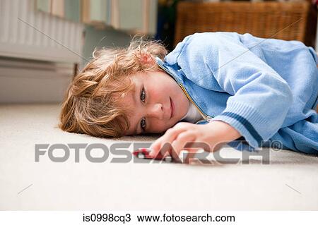 Young boy lying on his side playing with a toy car View Large Photo Image Stock Image - Young boy lying on his side playing with a toy car. Fotosearch