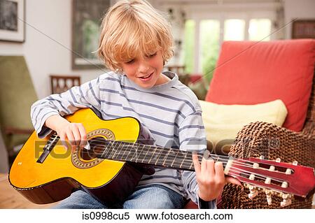 Young boy playing a guitar at home View Large Photo Image Stock Photography - Young boy playing a guitar at home. Fotosearch