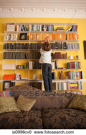 Young boy reaching up to get a book from a bookcase View Large Photo Image Stock Image - Young boy reaching up to get a book from a bookcase. Fotosearch