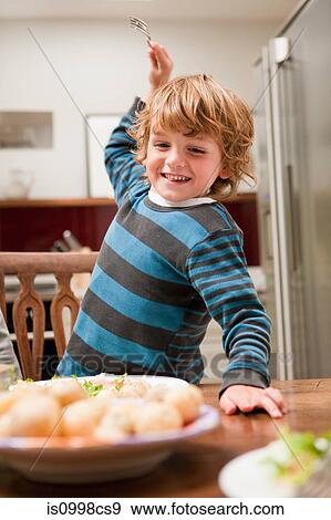 Young boy with fork raised about to stab potato View Large Photo Image Stock Photo - Young boy with fork raised about to stab potato. Fotosearch
