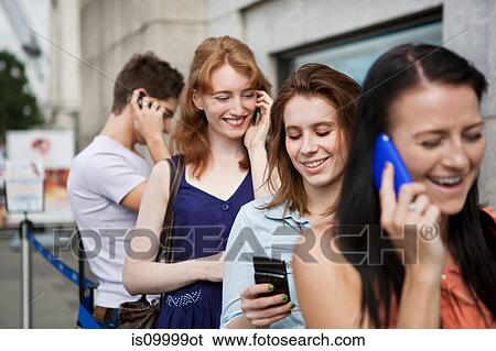 Four people in a queue, all using mobile phones View Large Photo Image Stock Photograph - Four people in a queue, all using mobile phones. Fotosearch