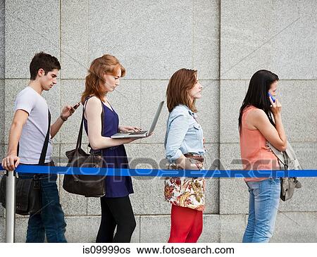 Four people in a queue, one using a laptop View Large Photo Image Stock Photograph - Four people in a queue, one using a laptop. Fotosearch