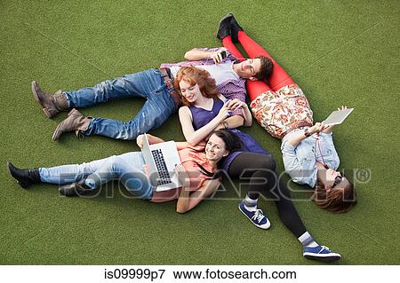 Four people lying down with a laptop, digital tablet and mobile phone View Large Photo Image Stock Photo - Four people lying down with a laptop, digital tablet and mobile phone. Fotosearch