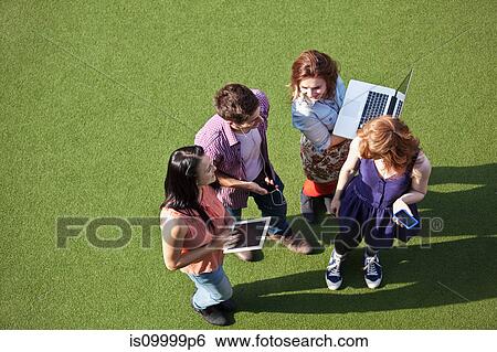 Four people standing on asto turf with technological equipment View Large Photo Image Stock Photograph - Four people standing on asto turf with technological equipment. Fotosearch