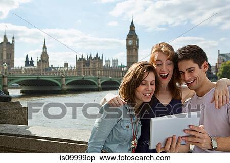 Stock Photography - Friends looking at a digital tablet together in London. Fotosearch