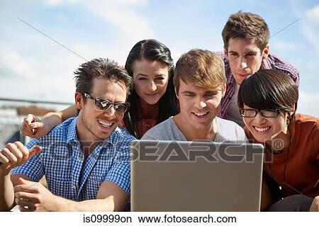 Friends looking at a laptop together View Large Photo Image Picture - Friends looking at a laptop together. Fotosearch