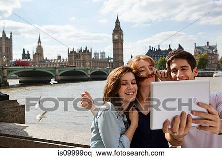 Stock Photography - Friends using a digital tablet in central London. Fotosearch